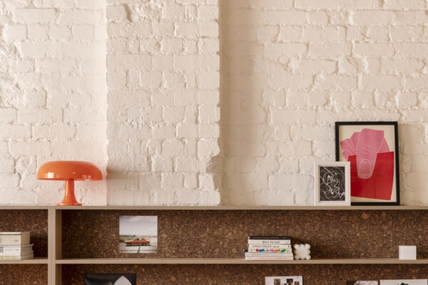 Custom shelving against painted brick walls in the Milanote Melbourne office fitout, adding texture, display space and character to the open workspace.