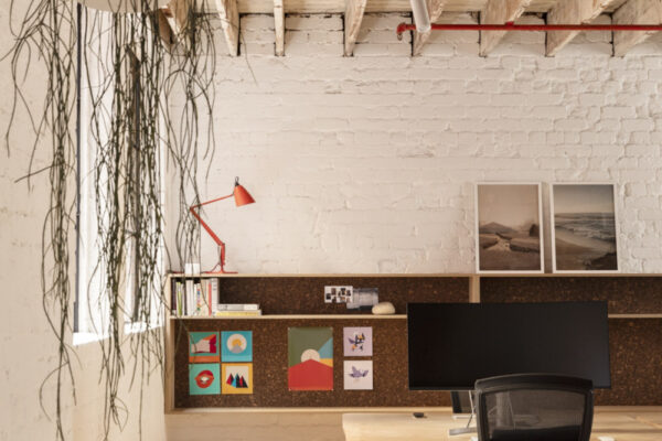 Custom shelving, timber flooring, and joinerty against painted brick walls in the Milanote Melbourne office fitout, adding texture, display space and character to the open workspace.