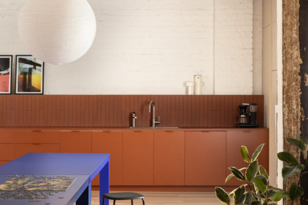 Breakout area in the Milanote Melbourne office fitout with a bold blue table, timber floors and exposed industrial ceiling details.
