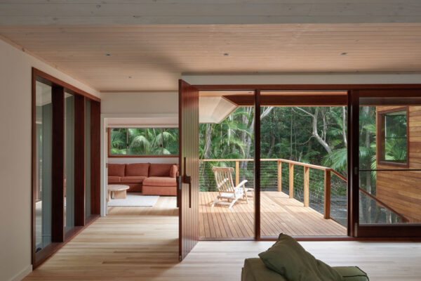 Open-plan living area in the MacGregor renovation in Suffolk Park, featuring timber-framed glazing, a generous deck and a seamless connection to the surrounding landscape.