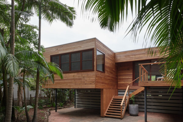 Timber-clad exterior in the MacGregor renovation in Suffolk Park, featuring an elevated deck area, outdoor stair and a strong connection to the surrounding coastal landscape.