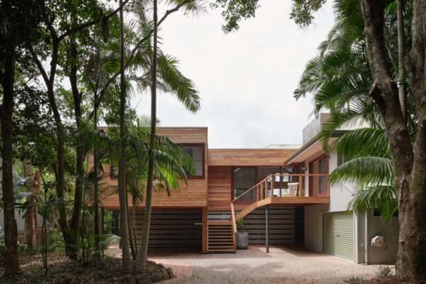 Timber-clad exterior in the MacGregor renovation in Suffolk Park, featuring an elevated deck area, outdoor stair and a strong connection to the surrounding coastal landscape.