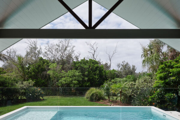 Pool and landscaped backyard at the MacGregor renovation in Suffolk Park, framed by a covered outdoor area and lush coastal planting.