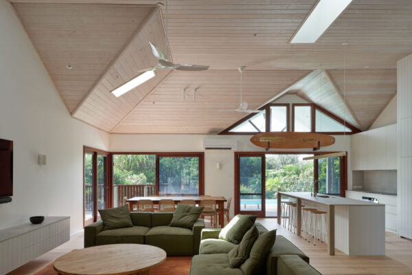 Open-plan kitchen, dining and living area in the MacGregor renovation in Suffolk Park, featuring vaulted timber-lined ceilings, expansive glazing and a seamless connection to the pool and deck.
