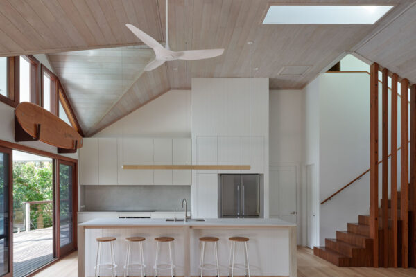 Open-plan kitchen in the MacGregor renovation in Suffolk Park, featuring timber-lined ceilings, an island bench, timber screening and warm coastal detailing.