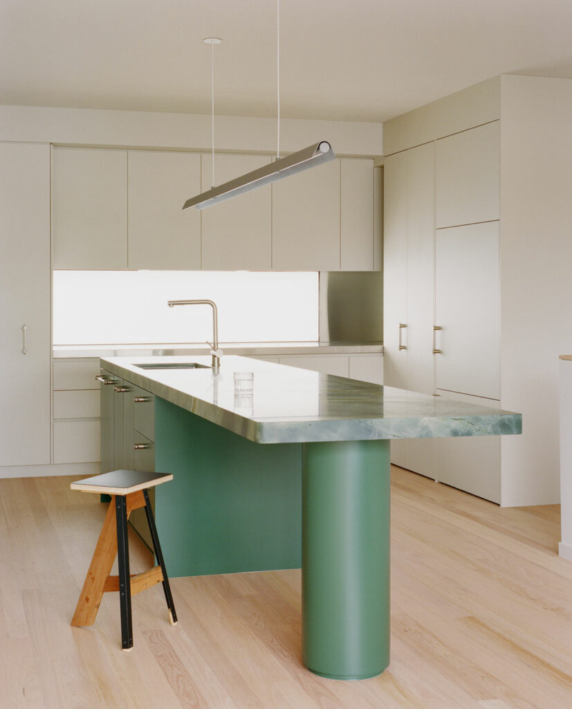 Minimal kitchen island in the Crown townhouse renovation in Richmond, Melbourne, featuring green joinery, a stone benchtop and a clean contemporary finish.