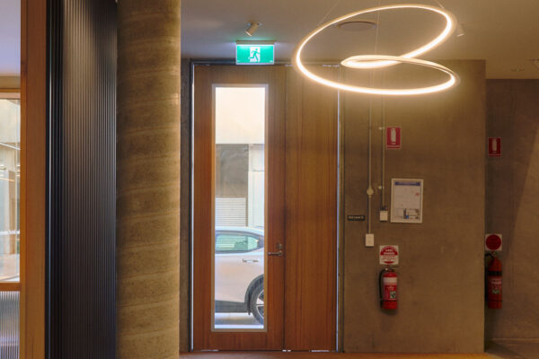 Entry area in the Fliteboard Office Fitout in Byron Bay, featuring polished concrete floors, exposed concrete columns, timber detailing and contemporary lighting.