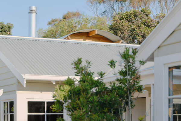 Exterior view in the Glaneuse project in Point Lonsdale, Victoria, featuring weatherboard cladding, a corrugated metal roof, white-framed windows.