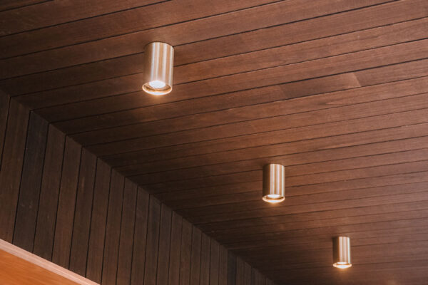 Timber wall and ceiling detail in the Top Pub BottleShop fitout in Mullumbimby, featuring integrated lighting, illuminated bottle display shelving and a rich moody finish.