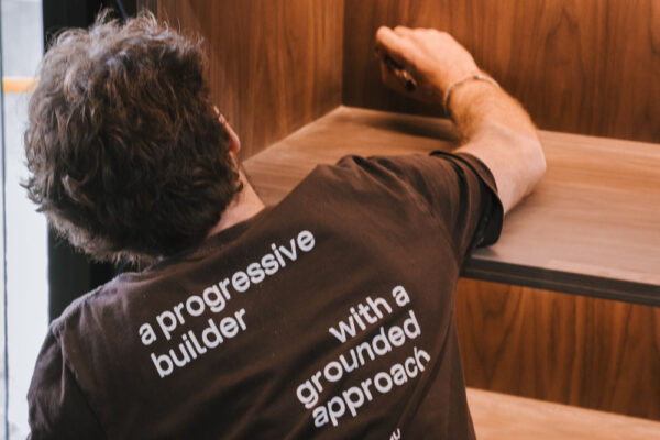 Well Grounded Building team member installing timber retail shelving in the Top Pub BottleShop fitout in Mullumbimby, showcasing custom joinery and on-site craftsmanship.
