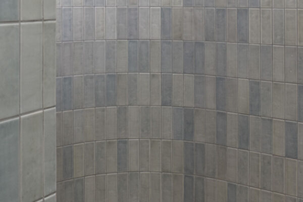 Curved shower wall in the Sunhaven Avenue home build in Skennars Head, featuring blue-grey tiles and a clean contemporary bathroom finish.
