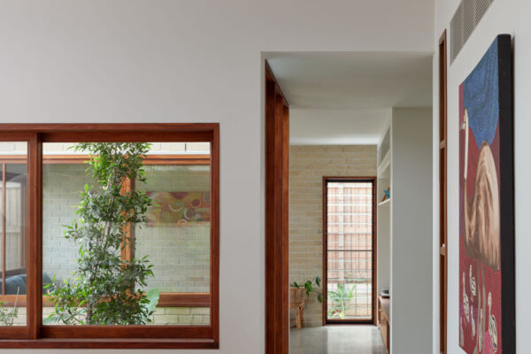 Interior hallway in the Sunhaven Avenue home build in Skennars Head, featuring exposed timber beams, large timber-framed glazing, polished concrete flooring and curved built-in bench seating.