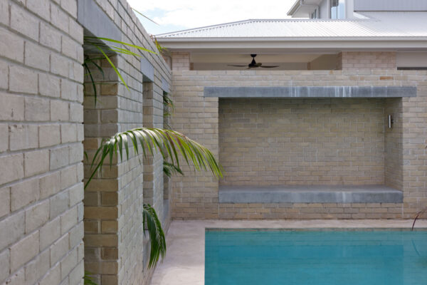 Pool area in the Sunhaven Avenue home build in Skennars Head, featuring light brick walls, concrete bench detailing, tropical planting and a private outdoor retreat.