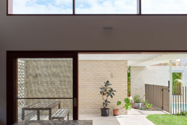Indoor-outdoor connection in the Sunhaven Avenue home build in Skennars Head, featuring high-level glazing, sliding doors, a stone island bench and a covered outdoor living area.