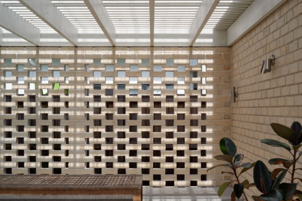 Outdoor living area in the Sunhaven Avenue home build in Skennars Head, featuring a white pergola, patterned brick screening, built-in bench seating and filtered natural light.