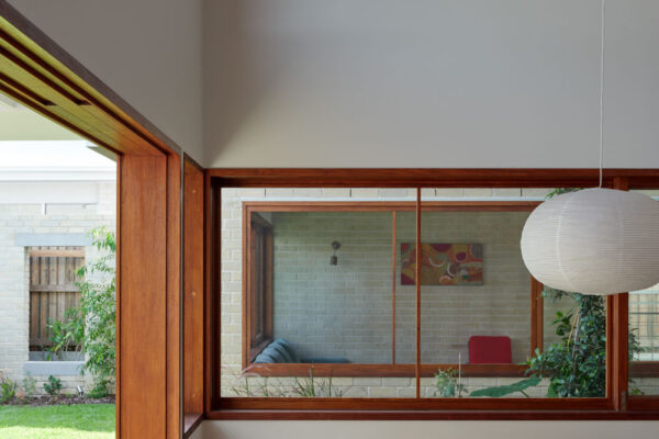 Dining area in the Sunhaven Avenue home build in Skennars Head, featuring exposed timber beams, built-in bench seating, large timber-framed glazing and a light-filled open interior.