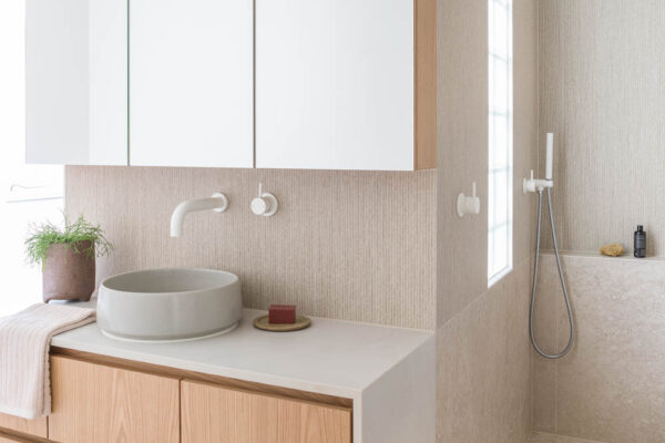 Bathroom vanity and shower area in the Park House build in Parkville, Melbourne, featuring timber joinery, textured wall tiles, a round basin and a clean minimalist finish.