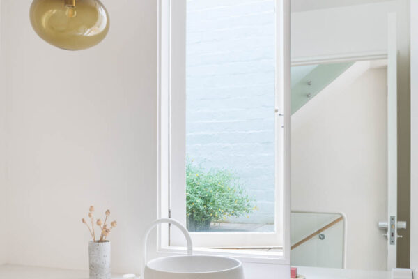 Bathroom vanity in the Park House build in Parkville, Melbourne, featuring timber joinery, a white benchtop, round vessel basin and a clean minimalist finish.