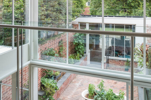 Park House build in Parkville, Melbourne, double-height glazing, circular steel columns, layered living spaces and views across the brick courtyard.