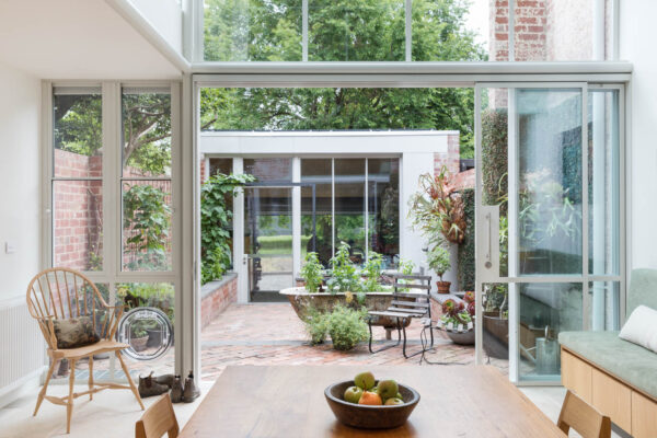 Dining area and brick courtyard in the Park House build in Parkville, Melbourne, featuring double-height glazing and a strong connection between indoor and outdoor living.